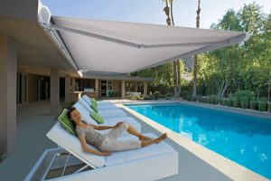 Katandra Interiors Busselton's Folding Arm Awnings protects the person relaxing on a chase lounge from the direct sunlight.