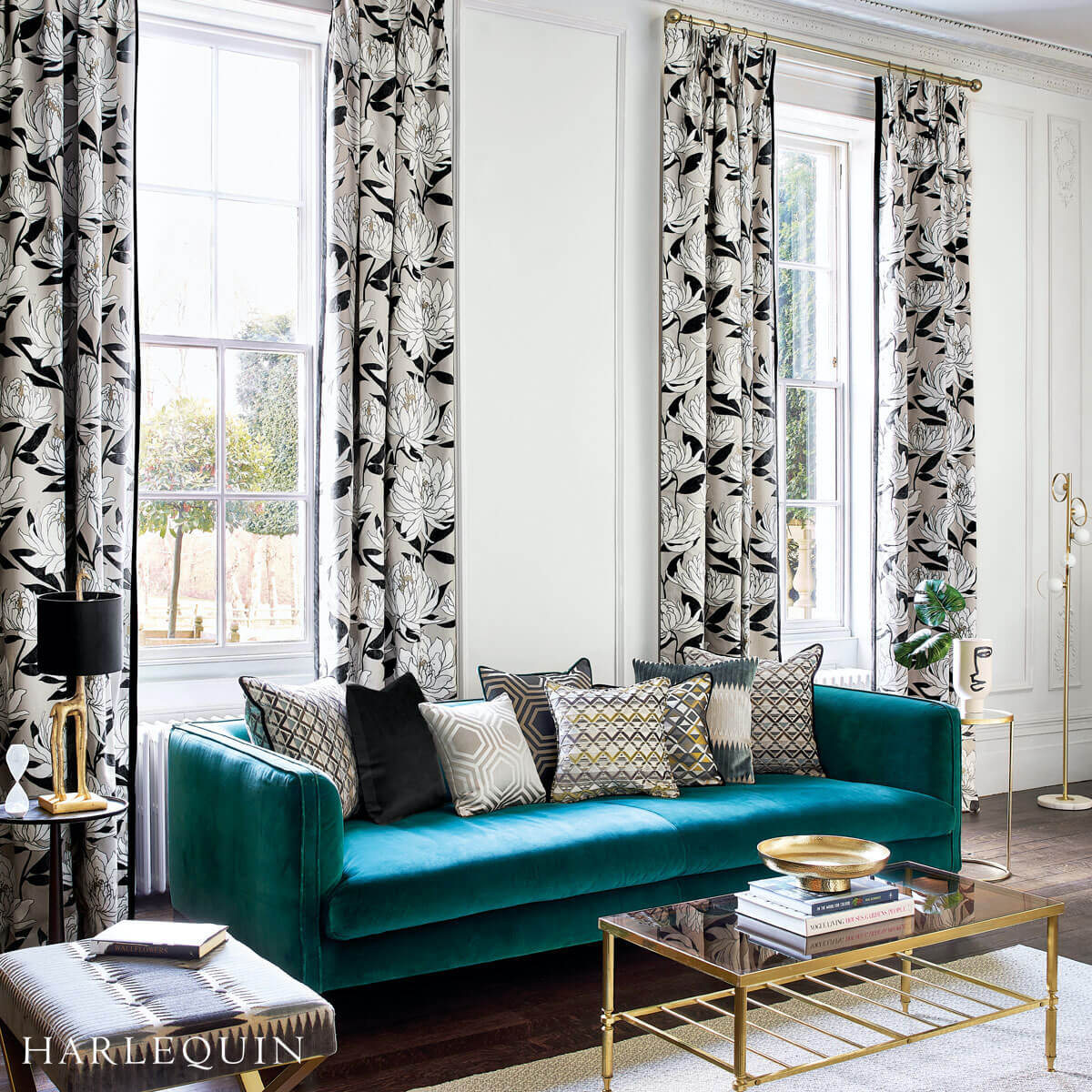 A room with wooden flooring and a blue-green nordic sofa with many pillows, a sliding glass window with a flower-designed extra long curtains installed by Katandra Interiors Busselton.