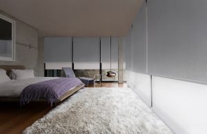 A bedroom with wooden flooring and white carpet, a glass window with gray and white Duette Shades Installed by Katandra Interiors Busselton.